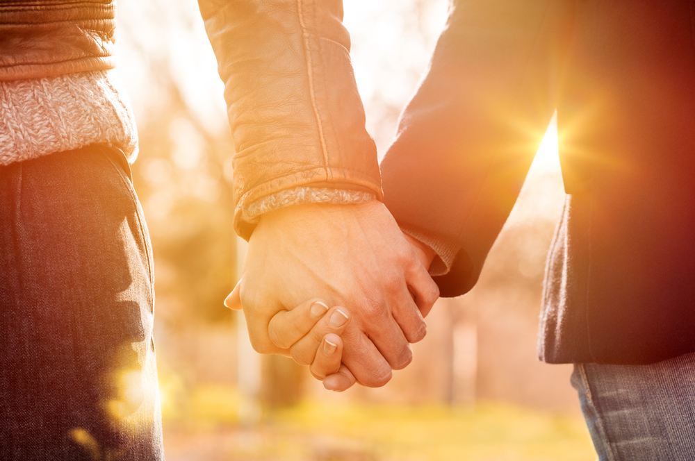 Closeup,Of,Loving,Couple,Holding,Hands,While,Walking,At,Sunset